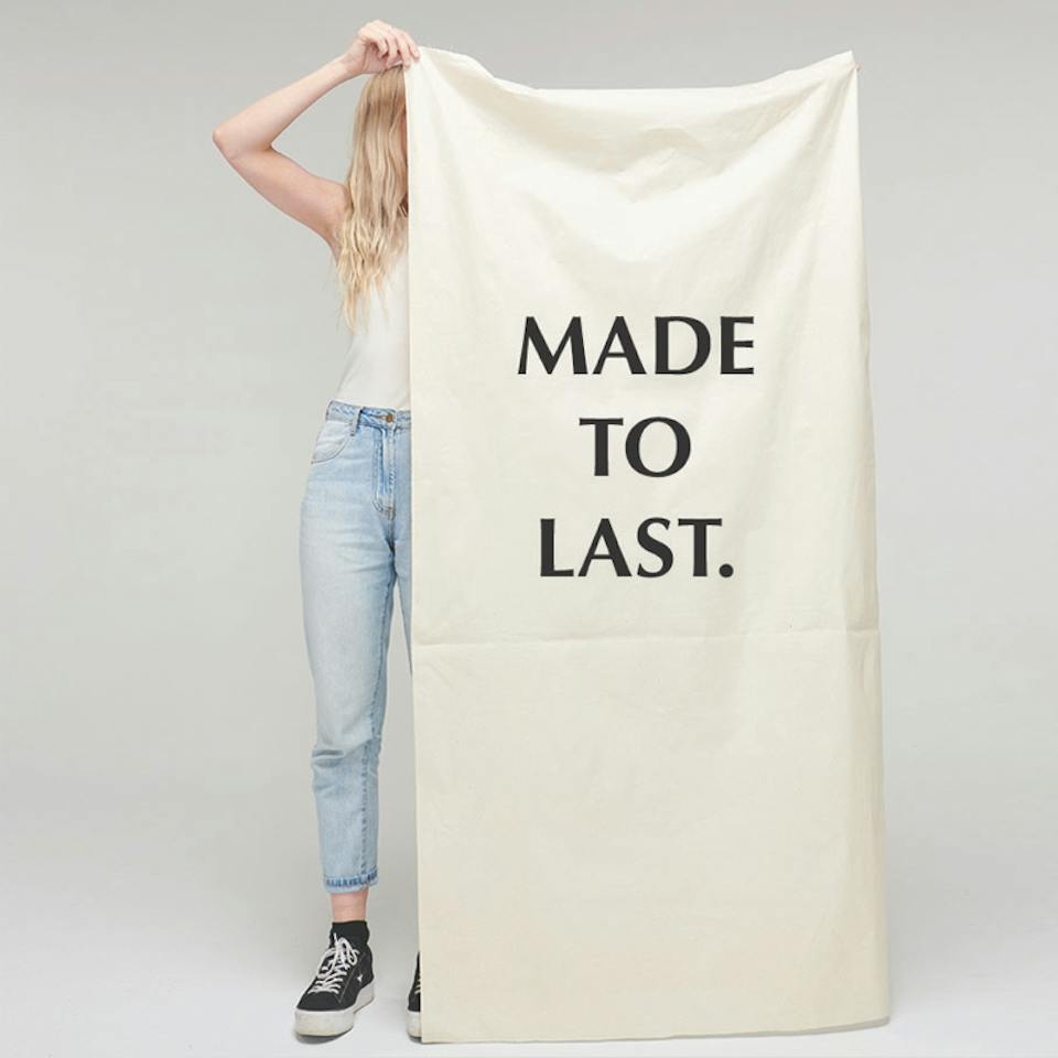 Person holds large canvas with 'Made to Last.' on front.